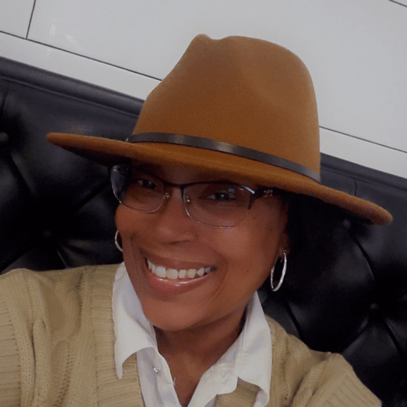 Latisha smiling with glasses and a hat on her head.