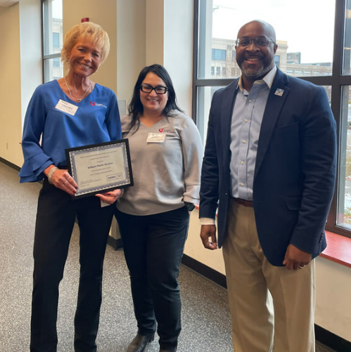 A male employee presents two women who work for a partner organization with an award