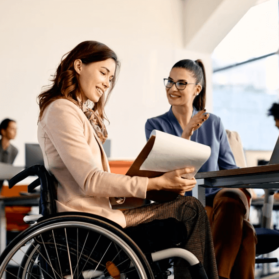 Two females sitting next to each other. One is in a wheelchair.