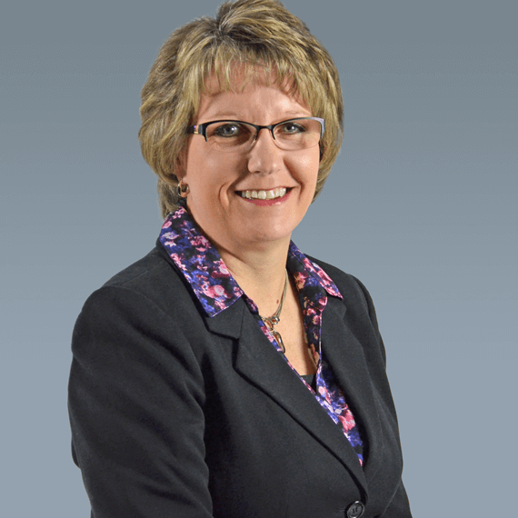 woman with glasses wearing a suit with a floral top 