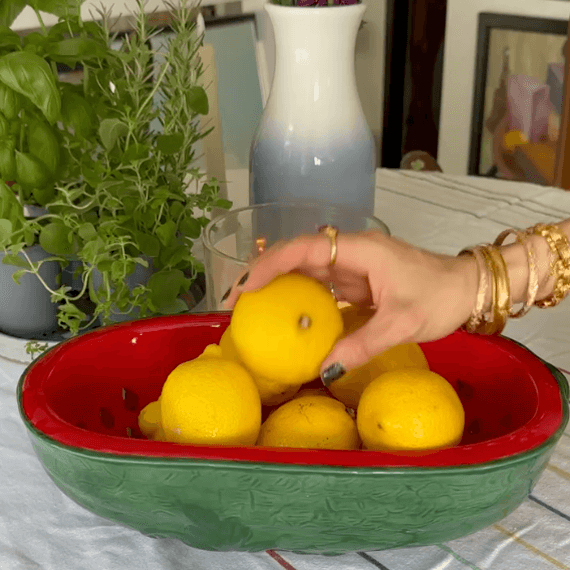 A red and green watermelon bowl with lemons in it.