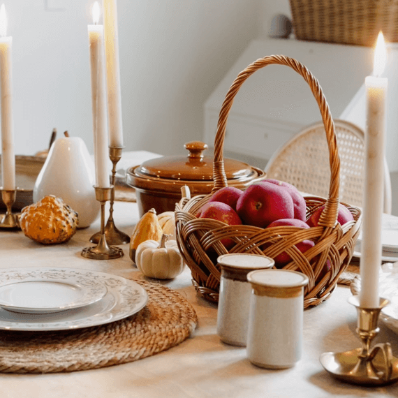 A fall tablescape with plates, wicker baskets and placemats and candles