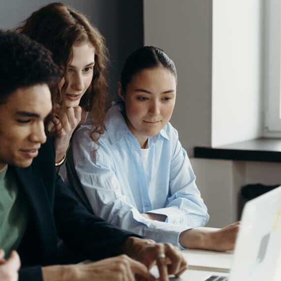 Photo of two women and a man working together on a computer