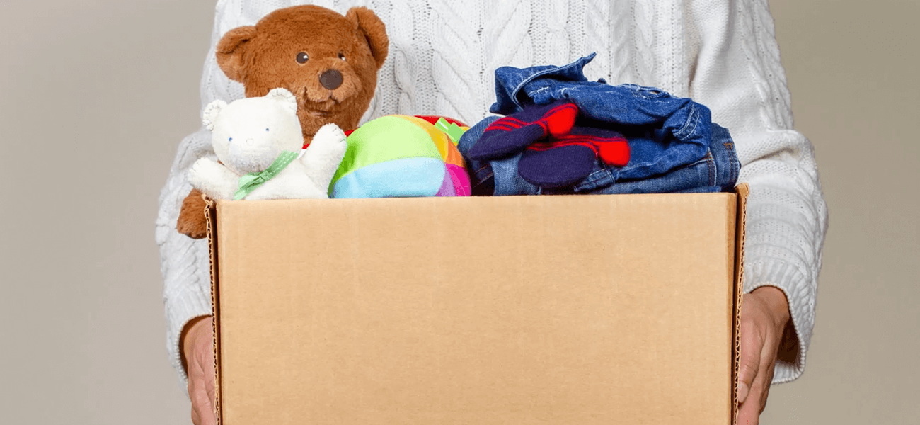 A cardboard box with toys and clothes in it