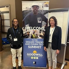 Construction program participant Rico stands beside a Goodwill banner with GESMN construction program director Becky Brink