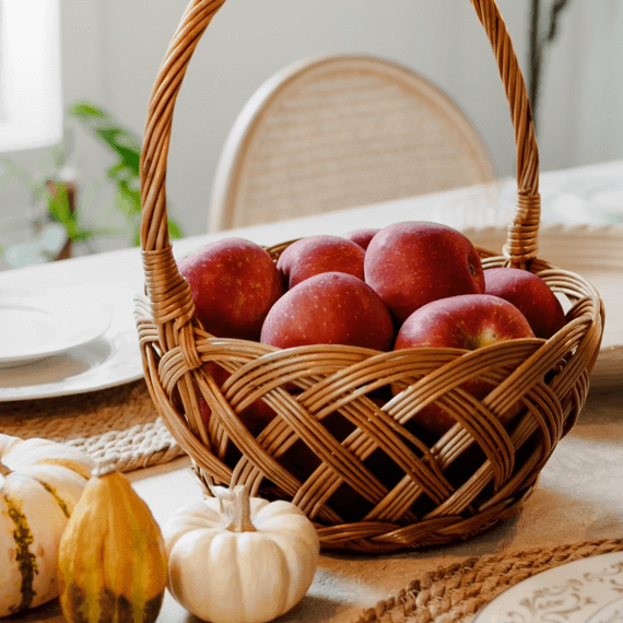 A wicker basket holding apples on a dining table