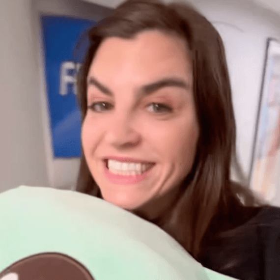 A female holding a baby grogu plush pillow in hand