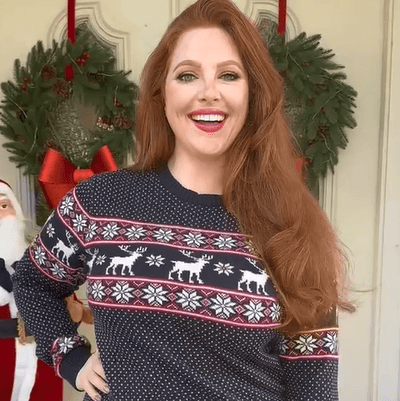 A woman with red hair wearing a navy wintery sweater