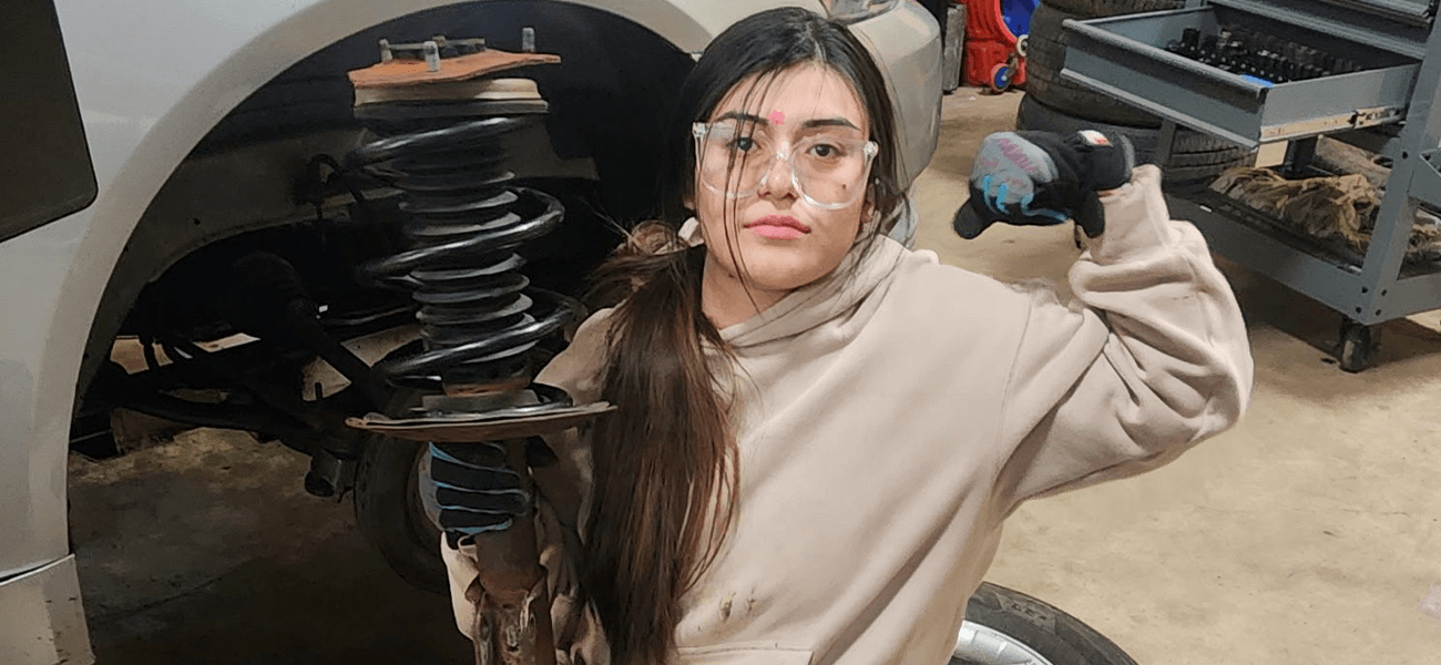 Michelle kneels by a car in the auto training area